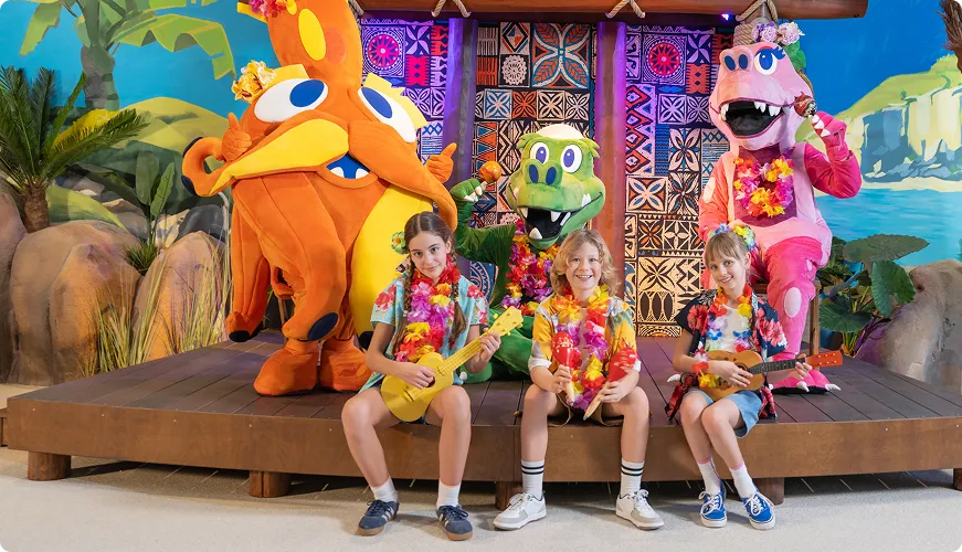 Dzieci z maskotkami dinozaura, krokodyla i hipopotama w tropikalnej scenerii z ukulele